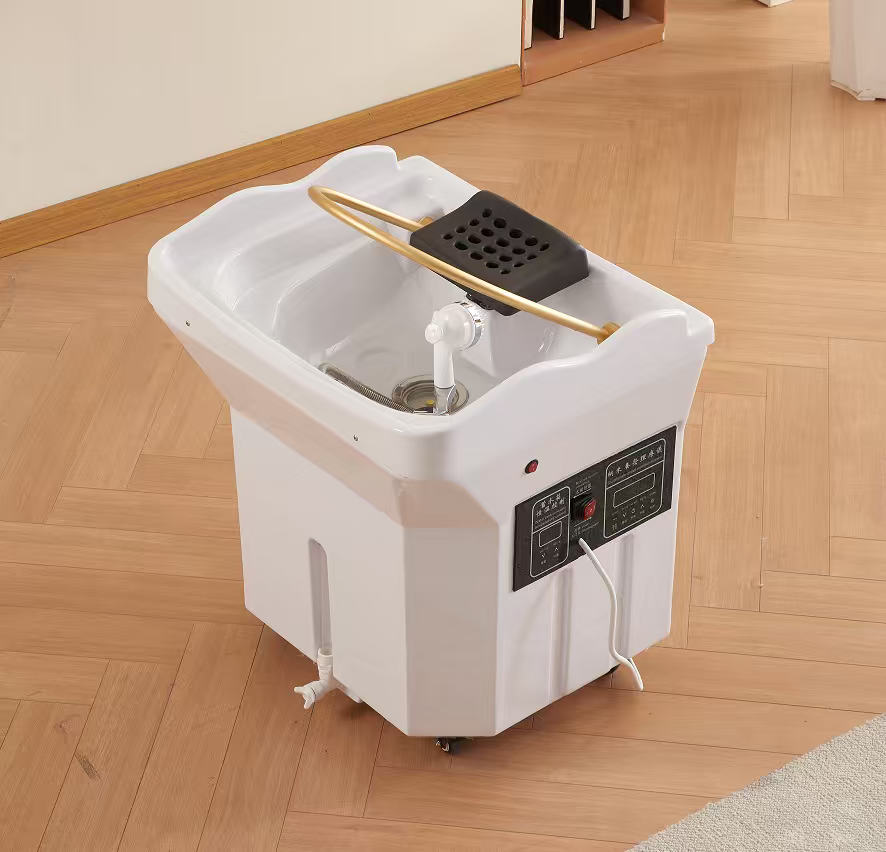 White compact home appliance with a shallow basin on top, grey control panel on the side, and wheels, designed for countertop use (appears to be a small cleaning/soaking device).