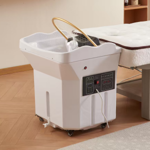 White wheeled pedicure spa basin with control panel and hose, placed beside a massage table for foot treatment