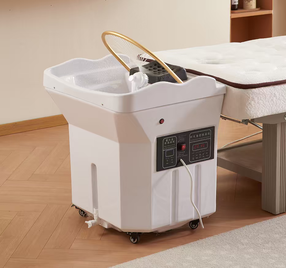 White wheeled pedicure spa basin with control panel and hose, placed beside a massage table for foot treatment